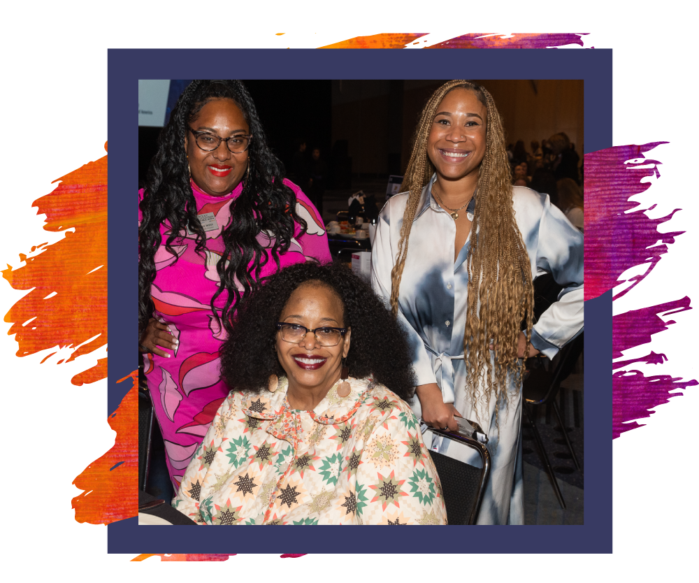 Three Black women smile while sitting at 2023 Annual Luncheon table