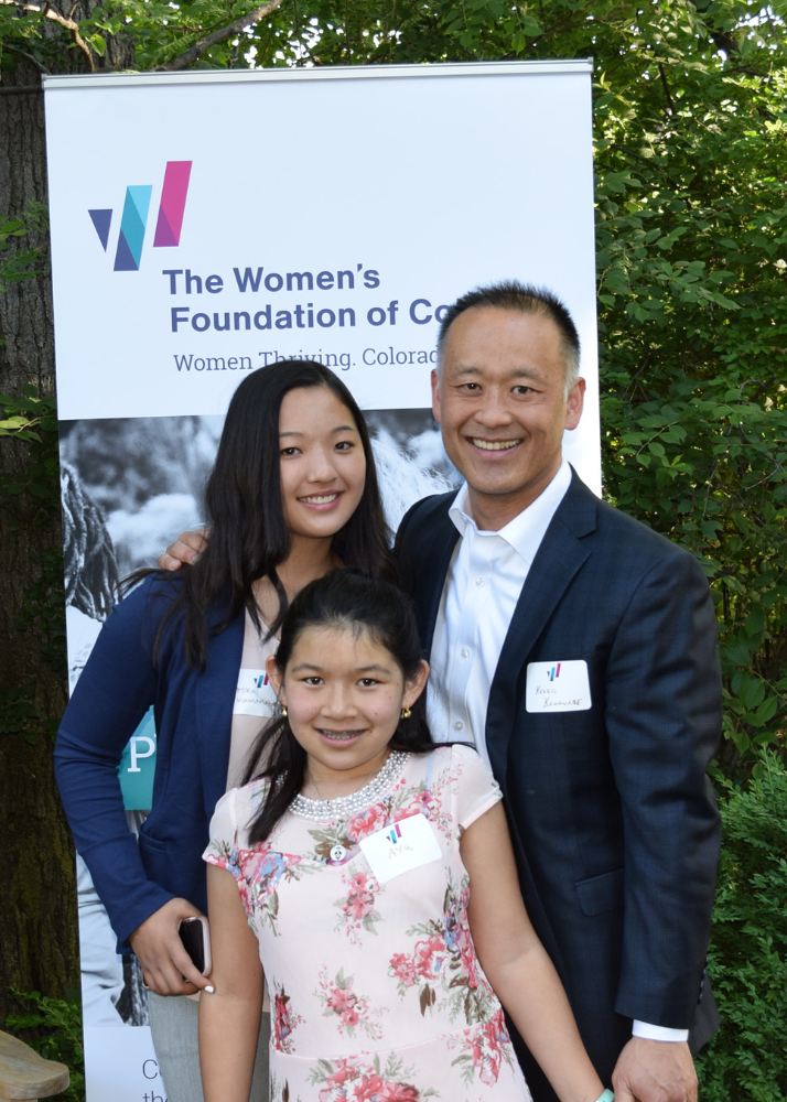 A dad and his young daughters smile together in front of WFCO banner