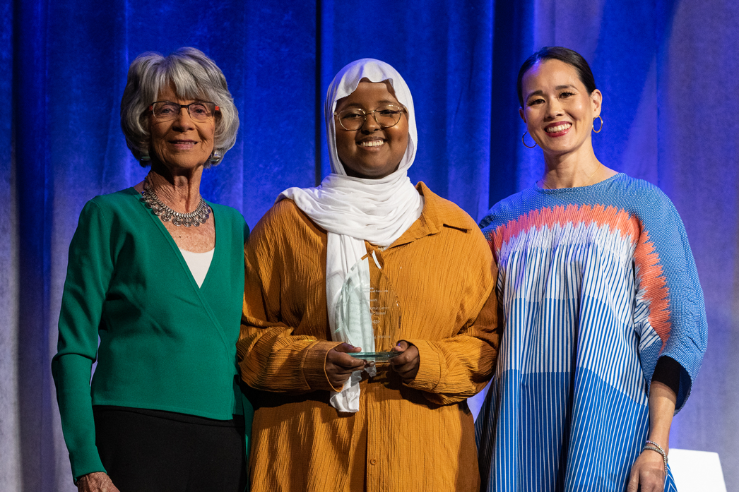 Dottie Lamm, Ayan Husein, and Tania Zeigler post onstage with Ayan's award at 2023 Annual Luncheon