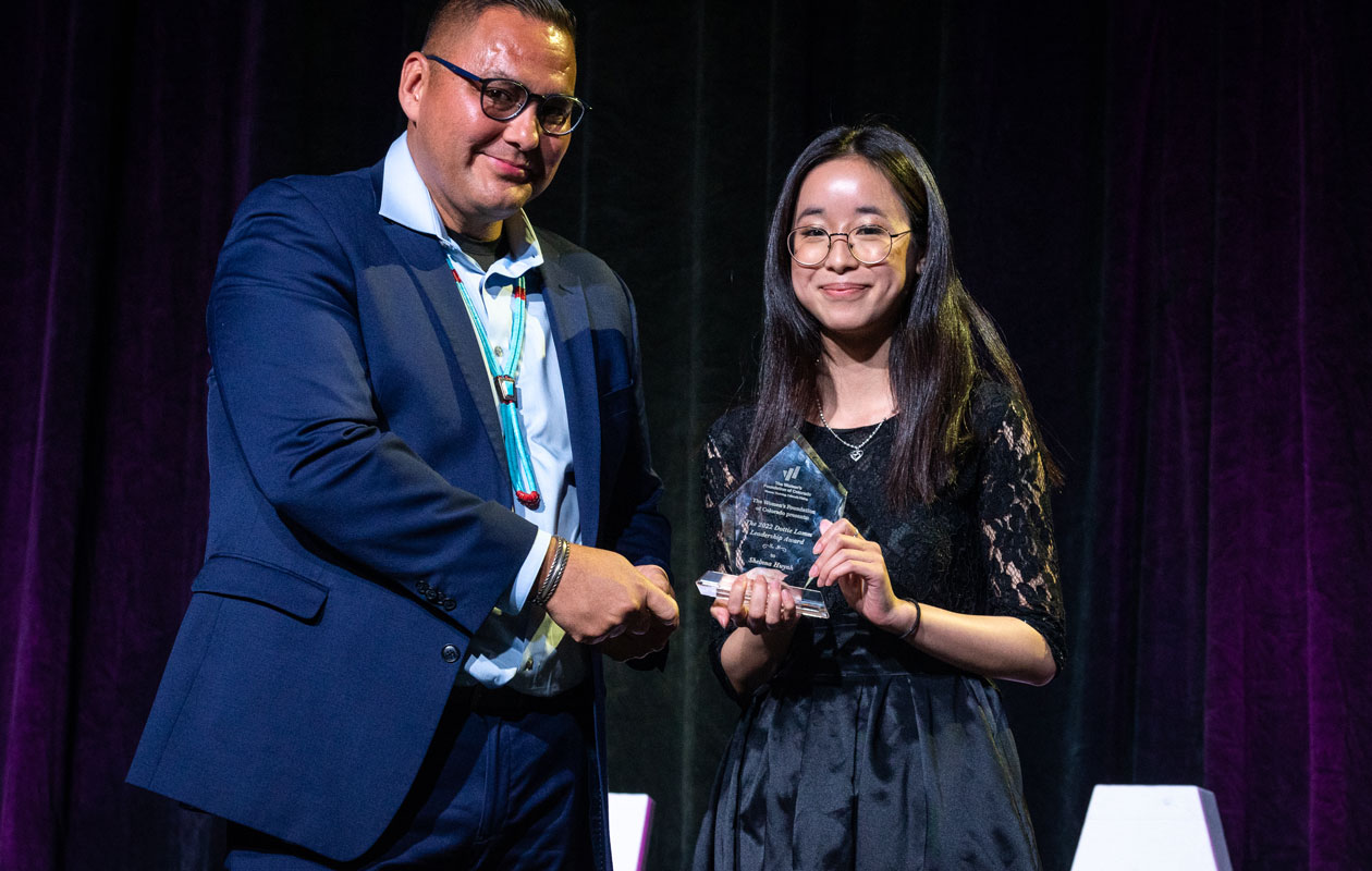 Shelnna Huynh of Denver stands on stage with WFCO Trustee Ray Foxworth with her Dottie Lamm Award